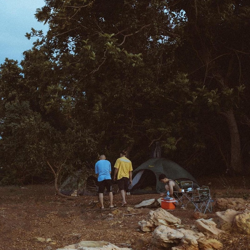 3 người tổ chức cắm trại ăn uống bên bờ đá