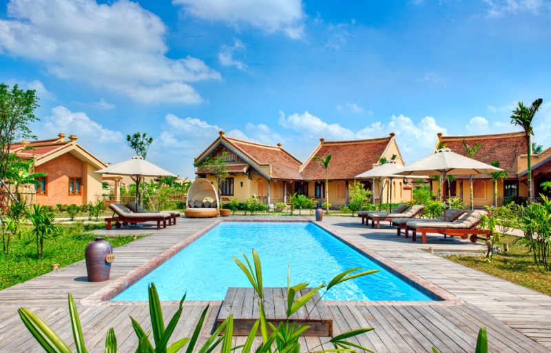 khuôn viên resort rộng rãi có bể bơi xanh mát ghế nghỉ và cây xanh
