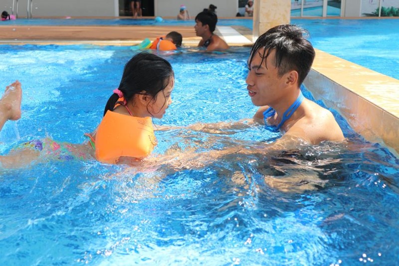 HLV đang dạy em nhỏ tập bơi trong hồ