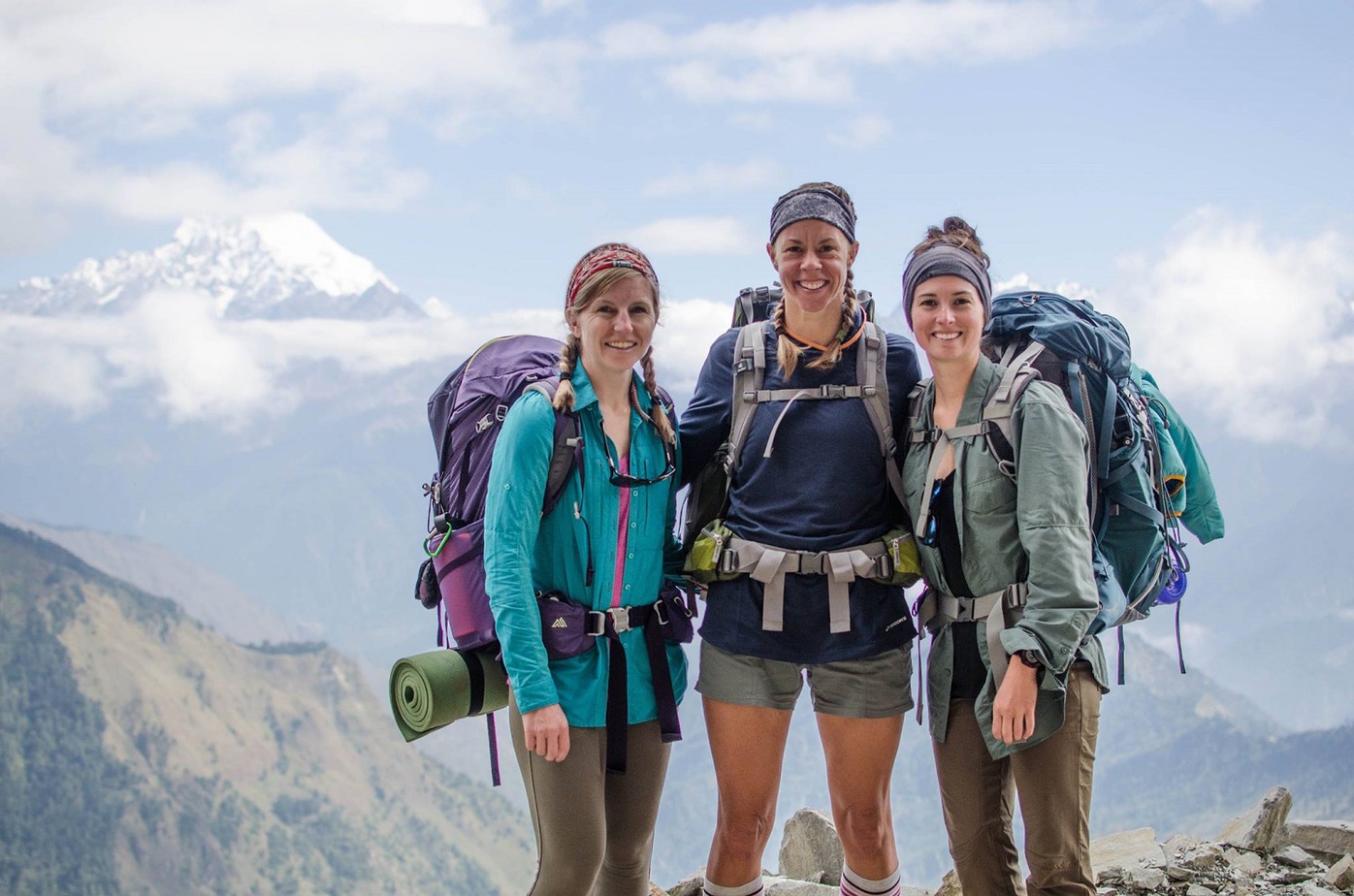 3 người phụ nữ đeo balo đứng trên đỉnh núi giữ khung cảnh mây ngàn