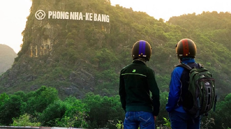 Hai chàng trai phượt xe máy chụp ảnh trước Phong Nha Kẻ Bàng