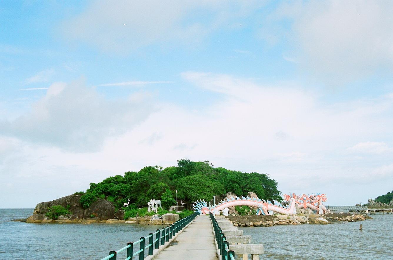Cây cầu dài nối ddaats liền và hòn đảo rợp bóng cây xanh, 2 bức tượng rồng bay lượn dưới chân đảo